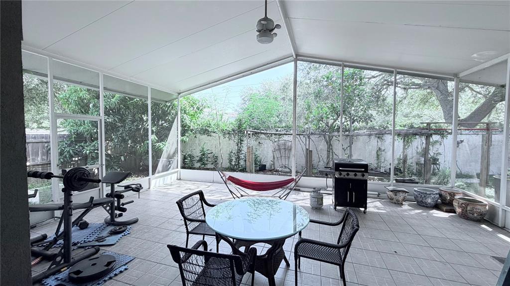 A screened-in patio features a glass dining table, gym equipment, a hammock, and a grill — 8503 PRINGLE WAY, TAMPA, FL