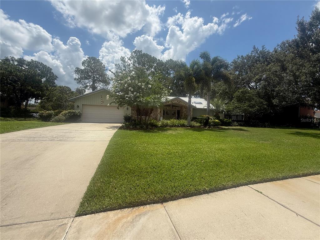 A single-story house with a two-car garage, stone facade, and a large front lawn — 2215 TONIWOOD LANE, PALM HARBOR, FL