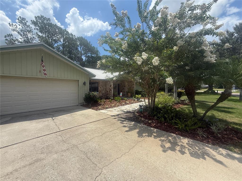 A light green house with a two-car garage and a stone-accented entryway — 2215 TONIWOOD LANE, PALM HARBOR, FL