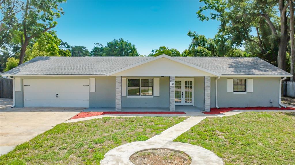 A single-story house with a gray exterior, a two-car garage, and a front porch — 501 ROSE AVENUE, FRUITLAND PARK, FL