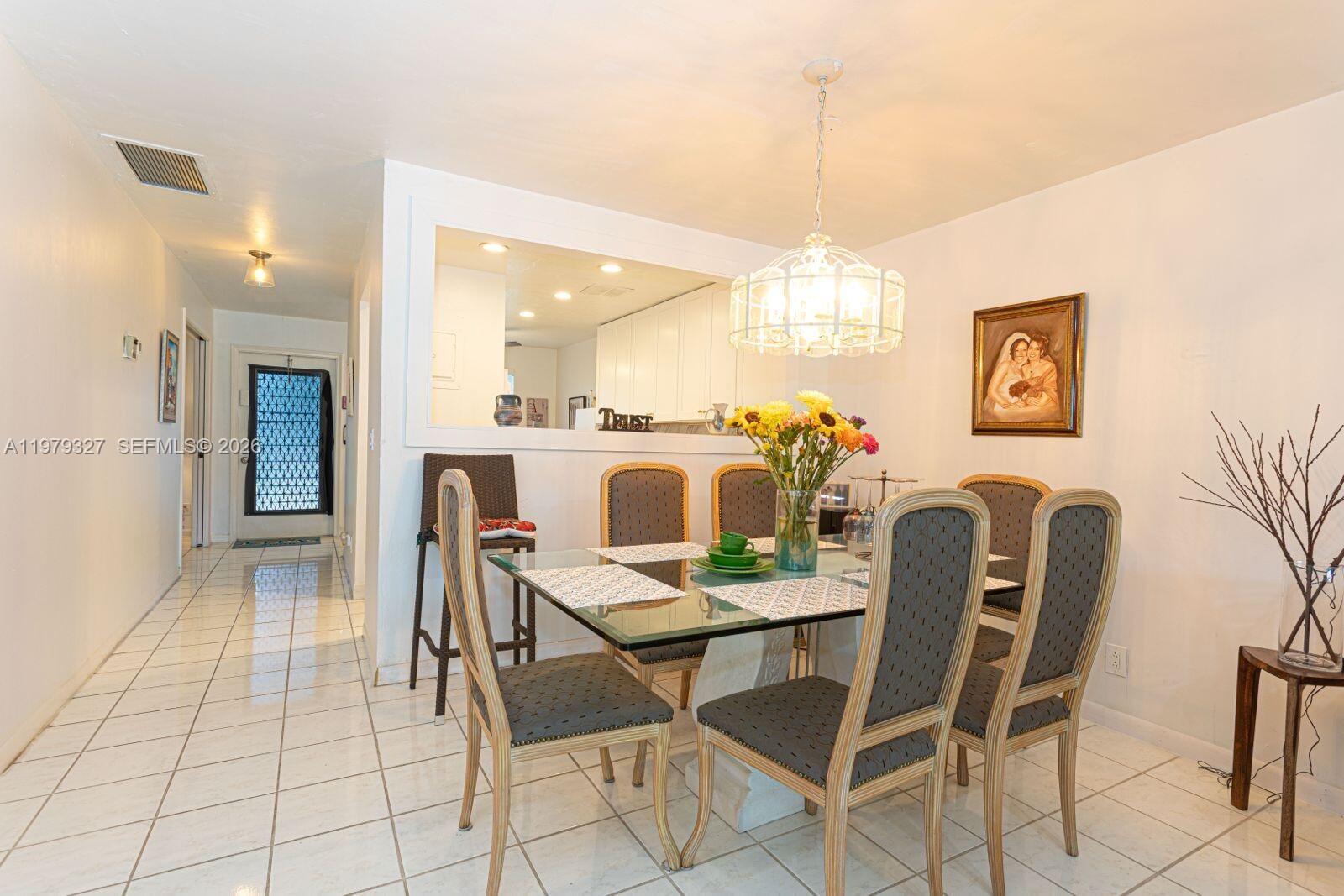 A dining room features a glass-topped table, upholstered chairs, and a pass-through to the kitchen — 1421 NW 19th Ter # 102, Delray Beach FL 33445, DELRAY BEACH, FL