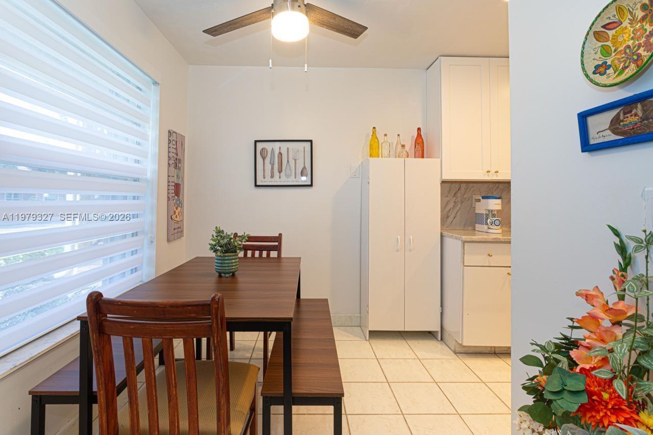 A dining area features a wooden table with a bench and chair under a ceiling fan — 1421 NW 19th Ter # 102, Delray Beach FL 33445, DELRAY BEACH, FL
