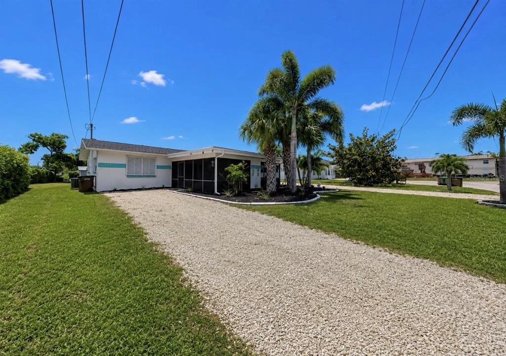 A single-story house with a gravel driveway, a screened porch, and palm trees — 4931 VICTORIA DRIVE, CAPE CORAL, FL