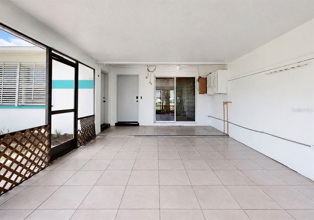 A covered patio features light-colored floor tiles, white walls, and a sliding glass door — 4931 VICTORIA DRIVE, CAPE CORAL, FL