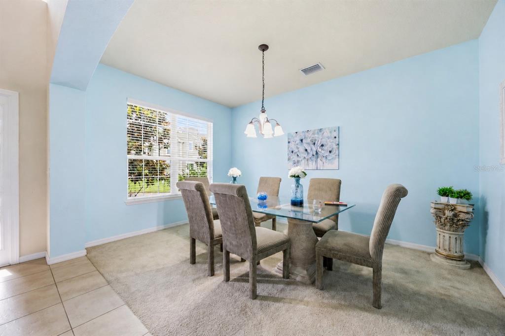 A dining room features a glass-topped table, six upholstered chairs, and light blue walls — 2820 CYPRESS GROVE COURT, ST CLOUD, FL