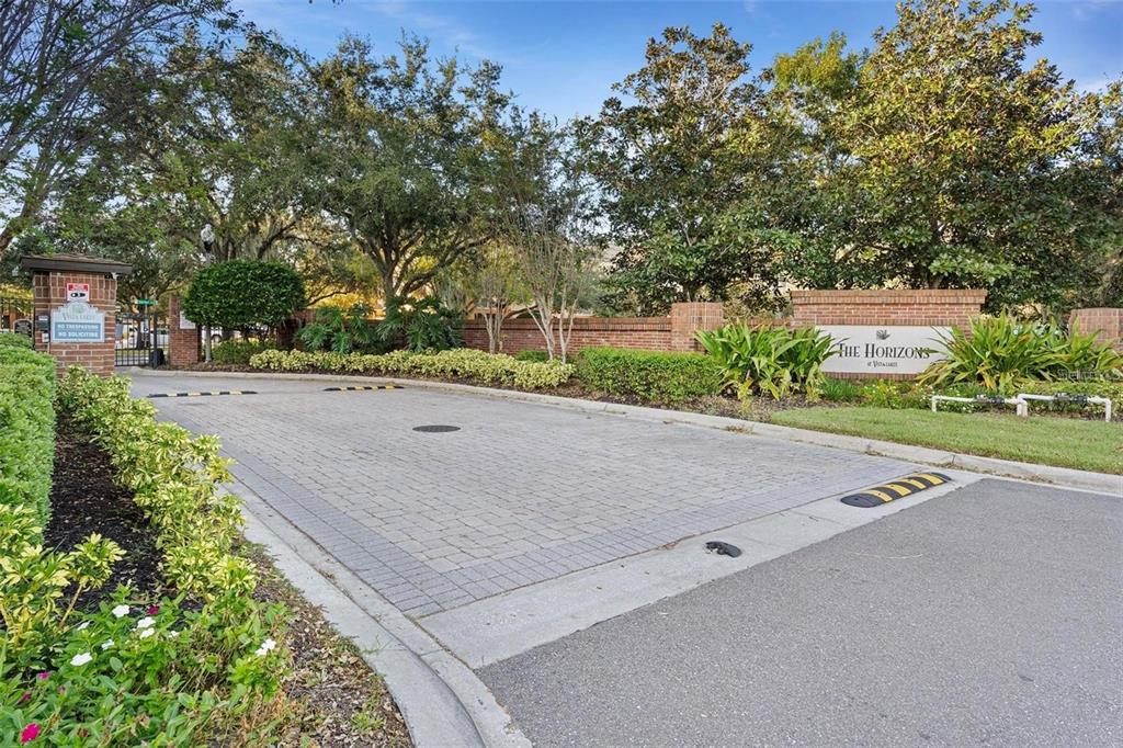 A paved entrance road leads to a brick sign for The Horizons at Vista Lakes — 6265 CONTESSA DRIVE UNIT 210, ORLANDO, FL