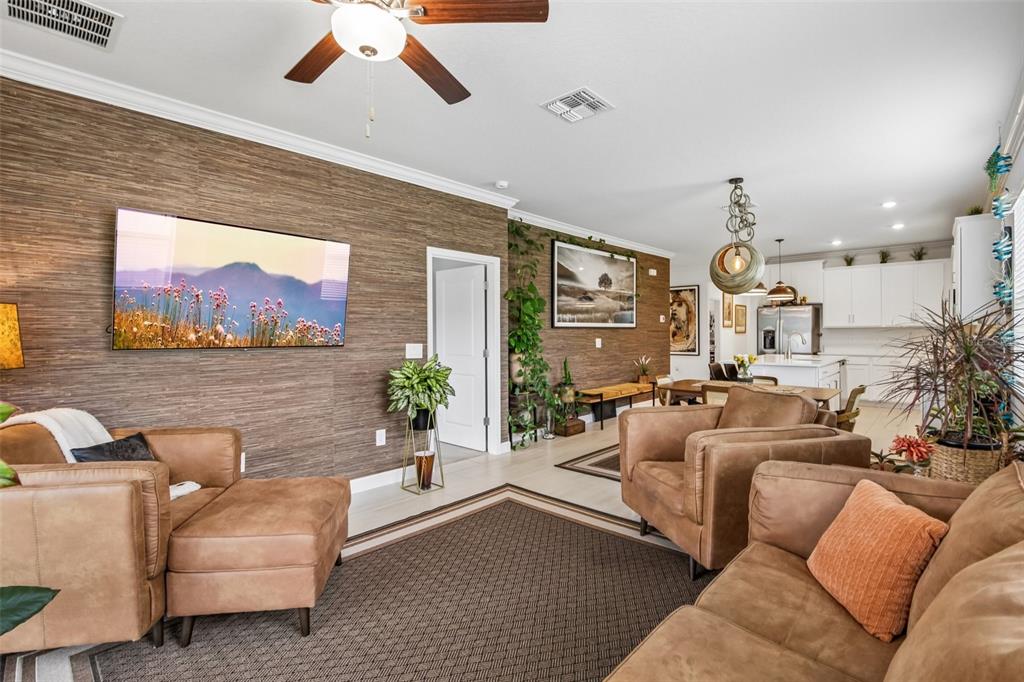 A living room features brown textured walls, leather furniture, and an open kitchen area — 12617 LILY QUARTZ LOOP, PARRISH, FL
