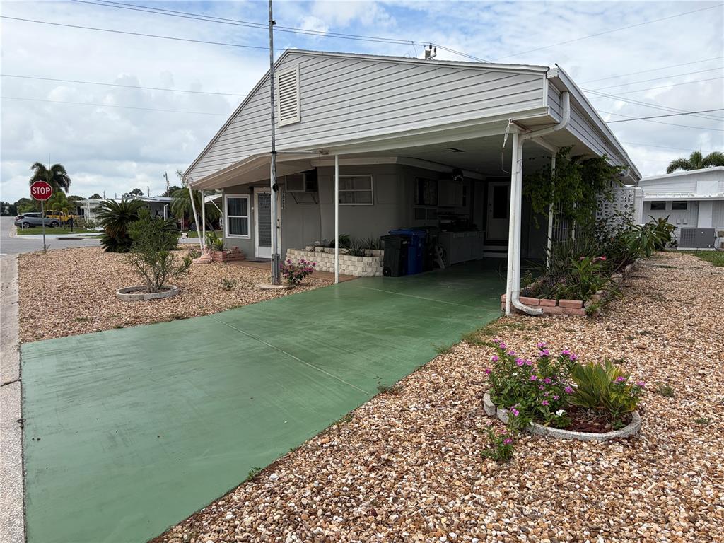 A single-story manufactured home with a green painted driveway and a covered carport — 5066 PEBBLE BEACH AVENUE, SARASOTA, FL
