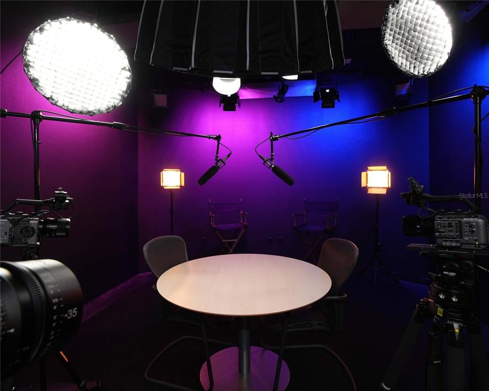A professional studio room features two cameras, microphones, lighting equipment, and a round table — 4705 S APOPKA VINELAND ROAD UNIT 210, ORLANDO, FL