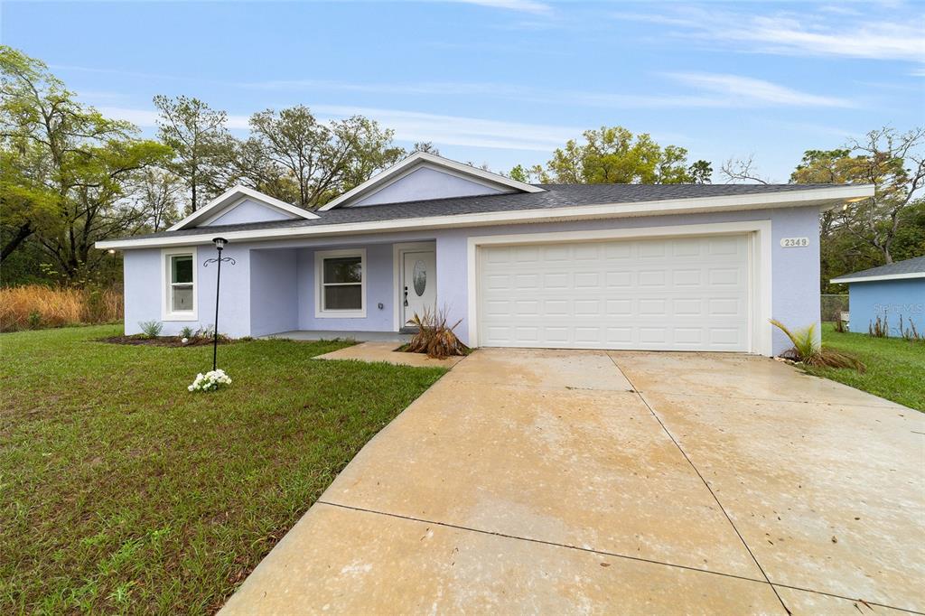 A light purple single-story house with a two-car garage and a concrete driveway — 2349 W JUAN VEGA LANE, DUNNELLON, FL