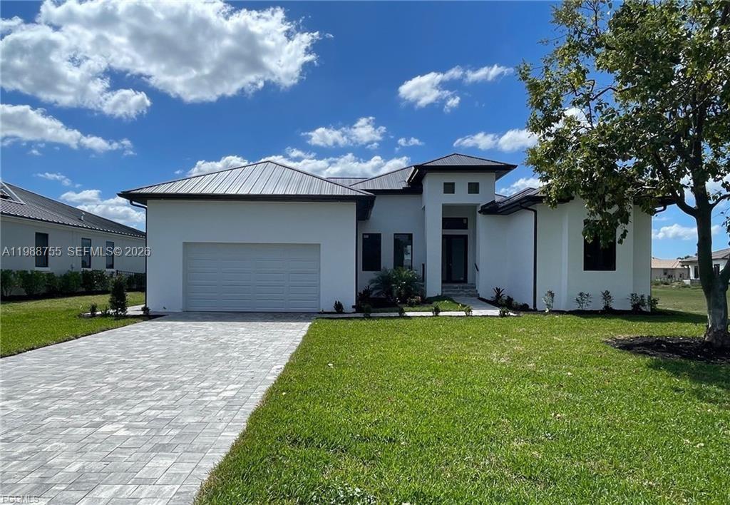 A modern, white single-story house features a metal roof, a paved driveway, and green lawn — 24249 Peppercorn Rd., Punta Gorda FL 33955, PUNTA GORDA, FL