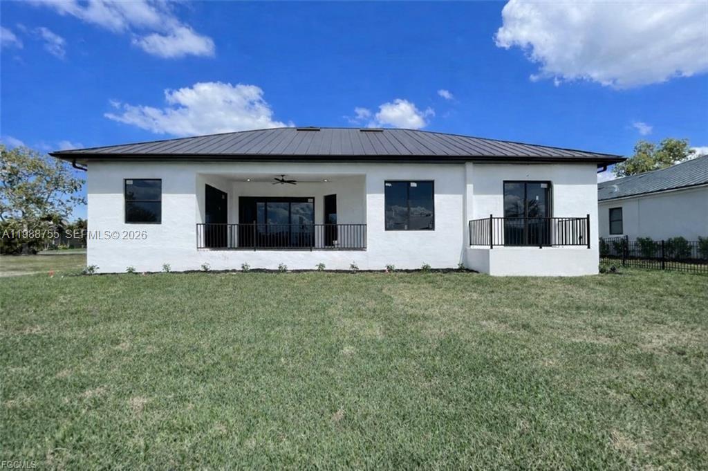 The rear exterior of a white, single-story house features a covered patio and metal roof — 24249 Peppercorn Rd., Punta Gorda FL 33955, PUNTA GORDA, FL