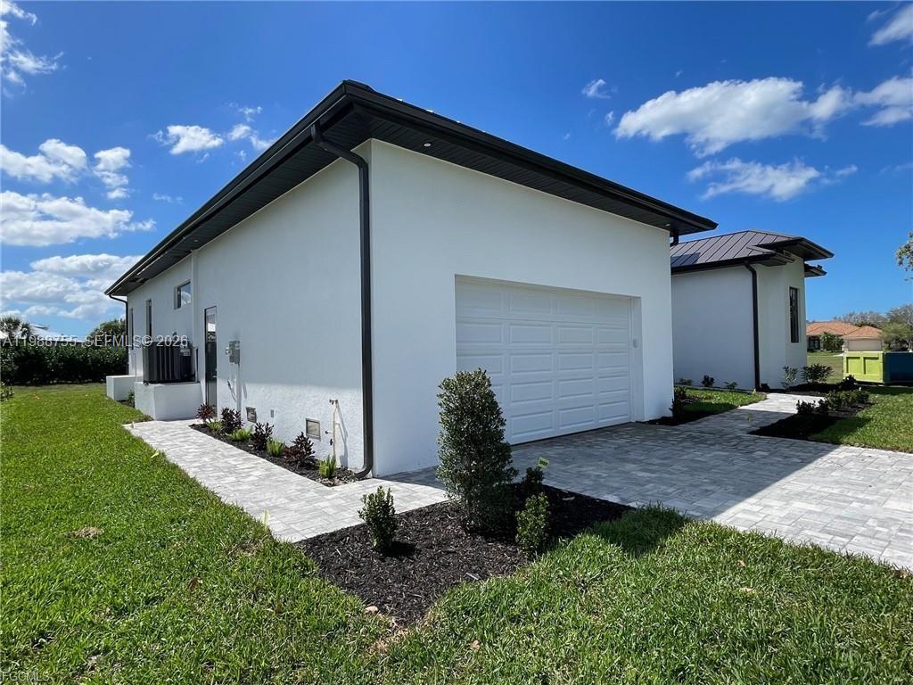 The exterior of a white modern house features a garage and a paved walkway — 24249 Peppercorn Rd., Punta Gorda FL 33955, PUNTA GORDA, FL