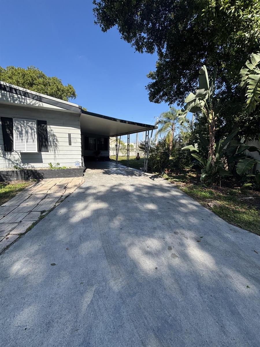 A concrete driveway leads to a covered carport attached to the side of a house — 3271 Fairway Drive, Pompano Beach FL 33069, POMPANO BEACH, FL