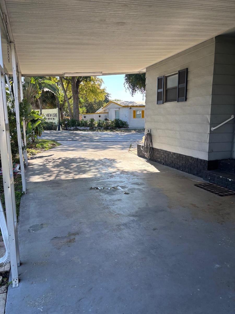 A concrete carport with a covered roof sits beside a house with gray siding — 3271 Fairway Drive, Pompano Beach FL 33069, POMPANO BEACH, FL
