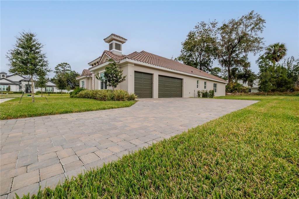 A beige house with a tiled roof and a paved driveway featuring two garage doors — 106 NEW LEATHERWOOD DRIVE, PALM COAST, FL