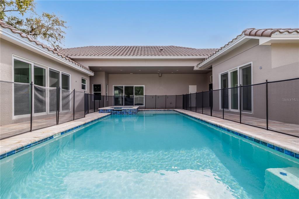 A rectangular swimming pool with a spa sits in a courtyard enclosed by a fence — 106 NEW LEATHERWOOD DRIVE, PALM COAST, FL
