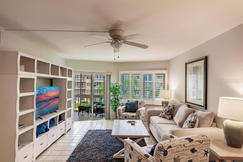 A living room features a white entertainment center, a beige sofa, and a sliding glass door — 1250 N PORTOFINO DRIVE UNIT 302, SARASOTA, FL