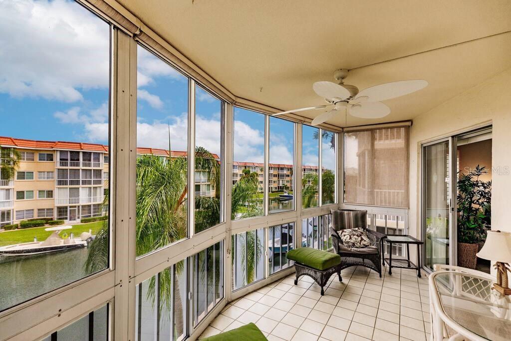 A screened-in balcony with tile flooring, a ceiling fan, and views of a canal — 1250 N PORTOFINO DRIVE UNIT 302, SARASOTA, FL