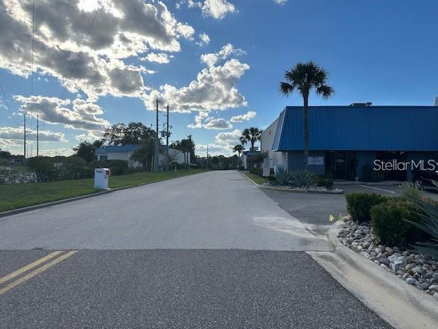 A paved road leads toward a commercial building with a blue metal roof and palm trees — 251 ALTAMONTE COMMERCE BOULEVARD UNIT 1402, ALTAMONTE SPRINGS, FL