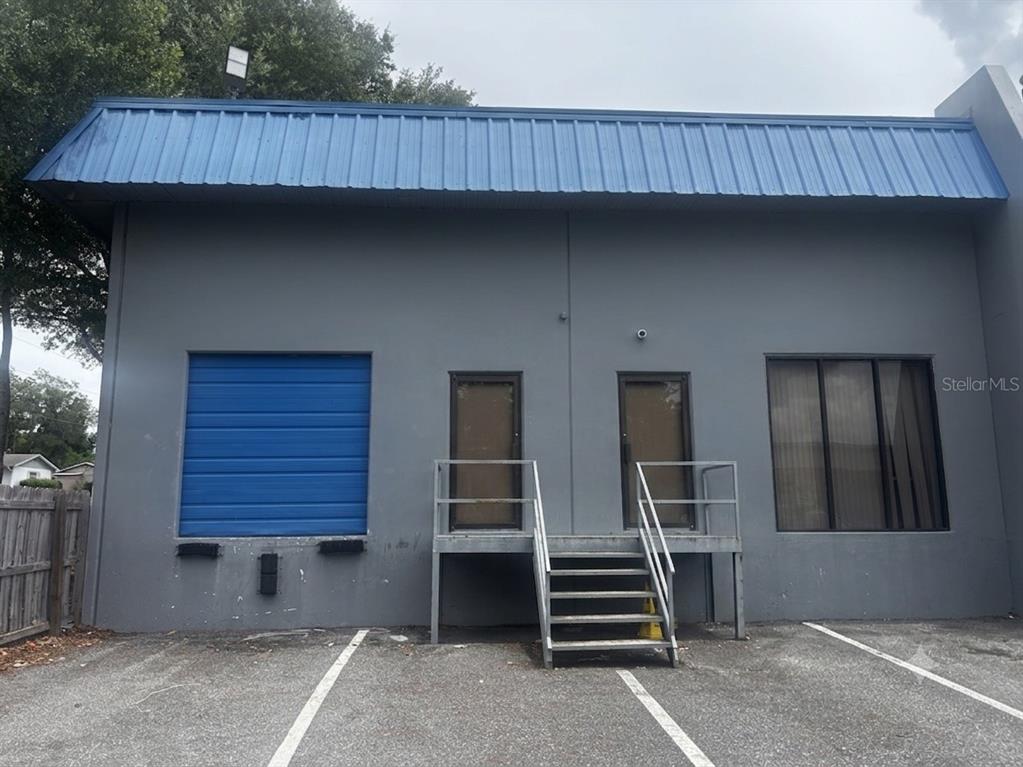 The exterior of a gray commercial building features a blue metal awning, loading door, and stairs — 251 ALTAMONTE COMMERCE BOULEVARD UNIT 1402, ALTAMONTE SPRINGS, FL
