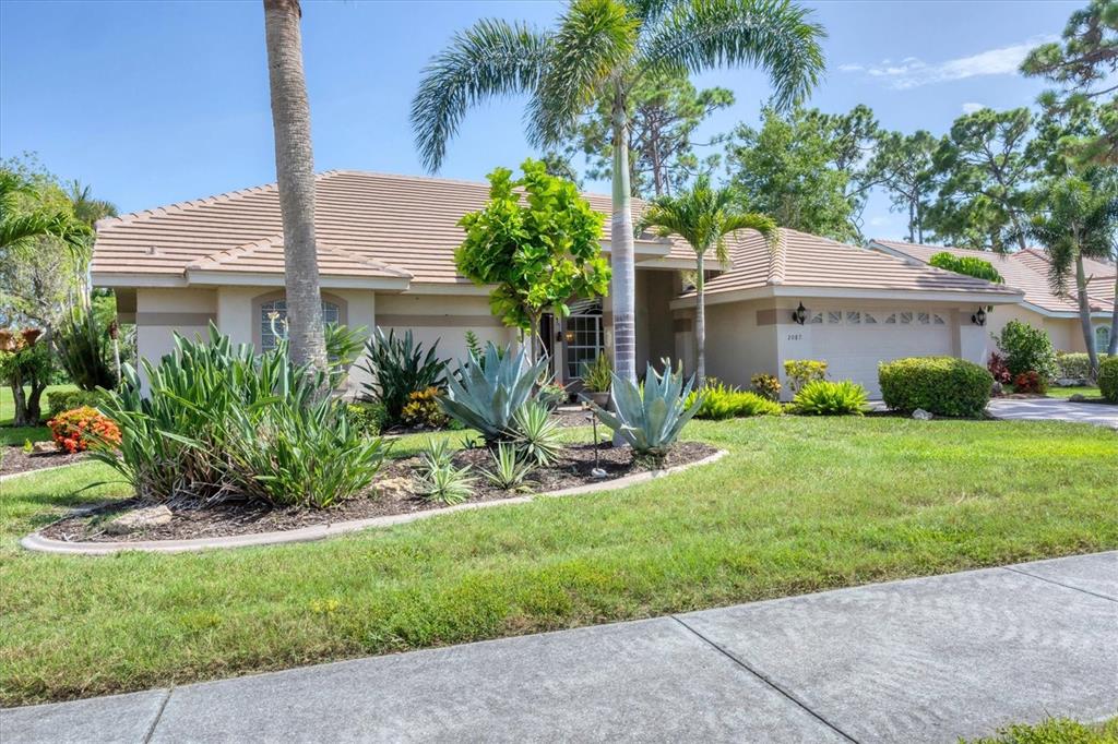 A single-story house with a tiled roof, palm trees, and landscaped front yard — 2087 TIMUCUA TRAIL, NOKOMIS, FL