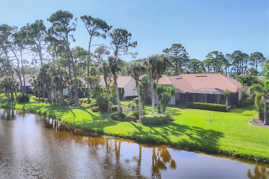 An aerial view of a house with a tiled roof and screened patio beside a canal — 2087 TIMUCUA TRAIL, NOKOMIS, FL