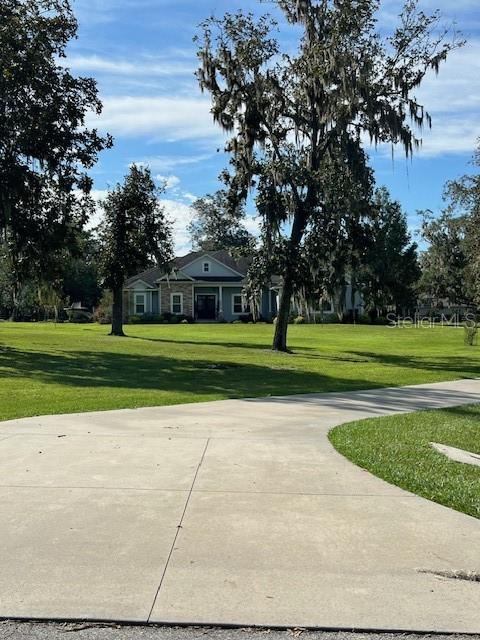 A concrete driveway leads toward a single-story house surrounded by large trees — 16604 NW STATE ROAD 45, HIGH SPRINGS, FL