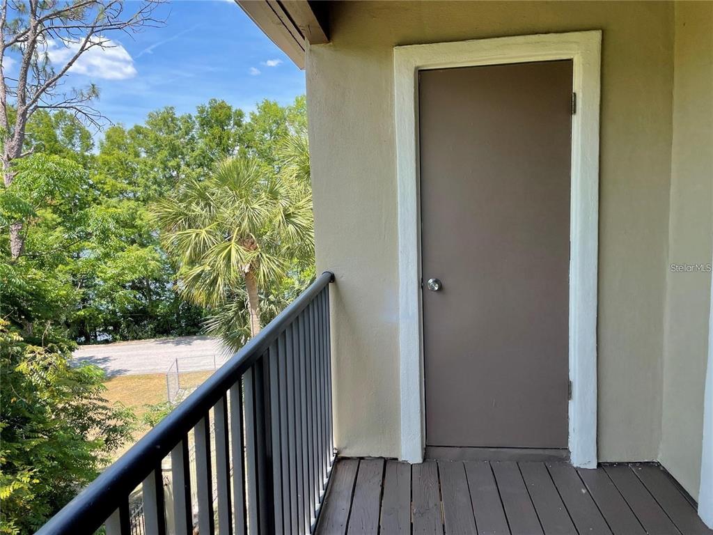 A balcony with a dark wood floor, metal railing, and a closed door — 199 AFTON SQUARE UNIT 309, ALTAMONTE SPRINGS, FL