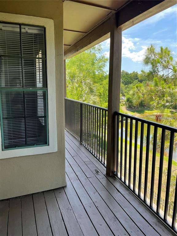 A covered balcony with wooden flooring and a black metal railing overlooks a pond — 199 AFTON SQUARE UNIT 309, ALTAMONTE SPRINGS, FL