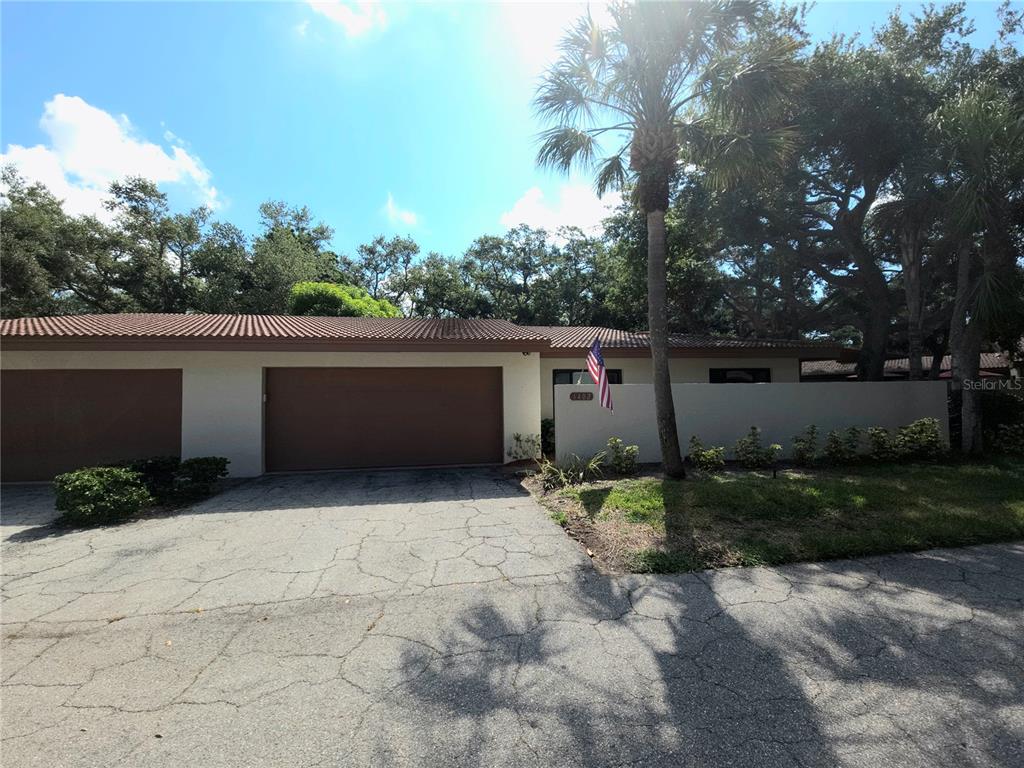 A single-story house with a two-car garage, a tiled roof, and a front privacy wall — 6402 MEADOWLARK LN, BRADENTON, FL