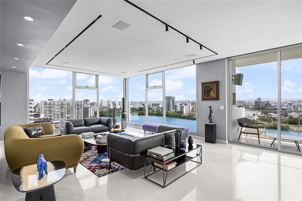 A modern living room with floor-to-ceiling windows overlooking a city skyline and water — 1002 ASHFORD AVENUE UNIT 14, CONDADO, PR