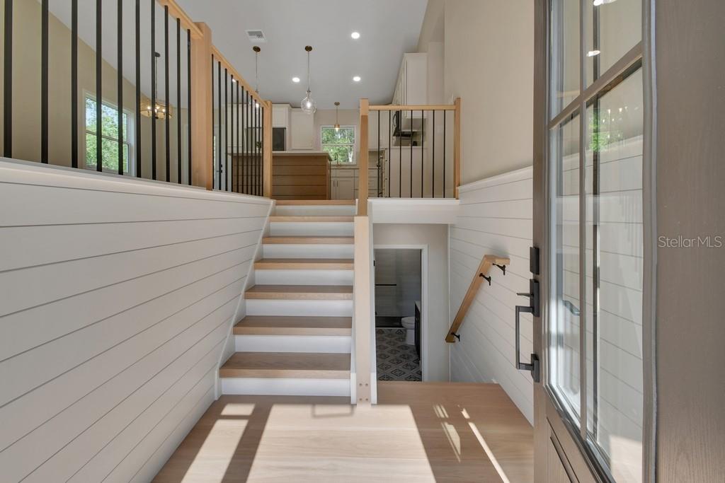 An entryway with light wood flooring, shiplap walls, and stairs leading up to a kitchen — 1530 DEERMOSS LANE, DELAND, FL