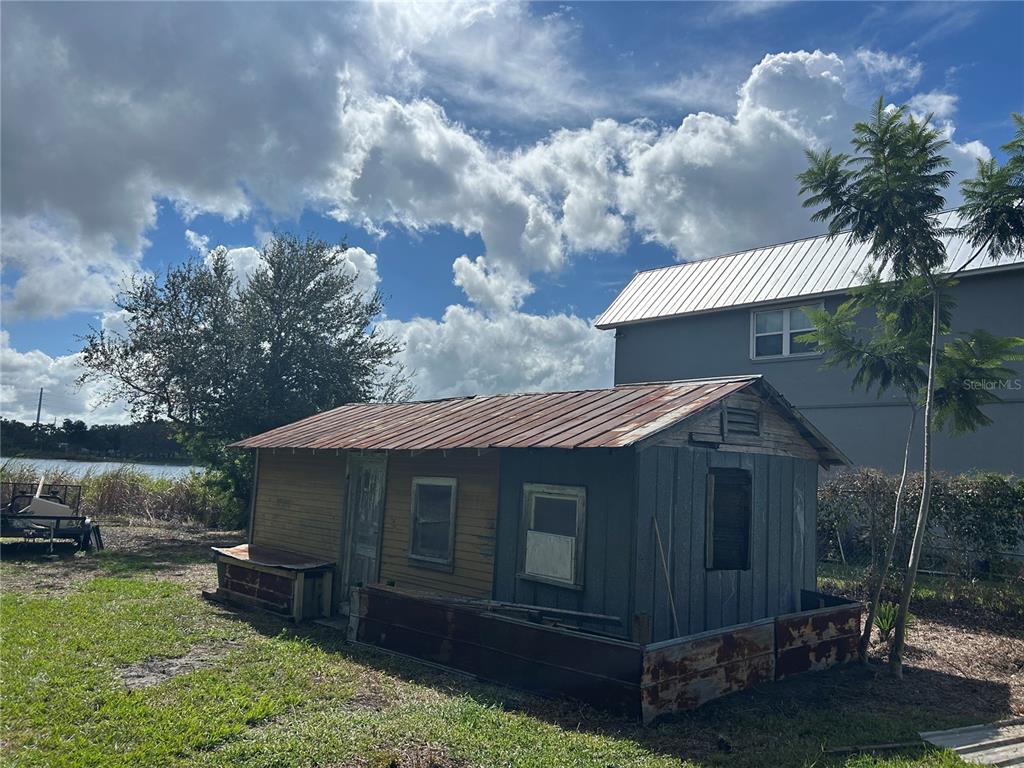 A weathered, small wooden shed with a rusted metal roof sits on a grassy lot — 2844 LAKE ALFRED ROAD, WINTER HAVEN, FL
