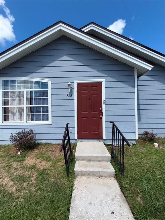 A blue-sided house features a red front door, a large window, and concrete steps — 862 CARIBBEAN DRIVE UNIT B, DAVENPORT, FL