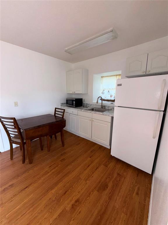 A small kitchen features white cabinets, a white refrigerator, a sink, and a wooden table — 862 CARIBBEAN DRIVE UNIT B, DAVENPORT, FL