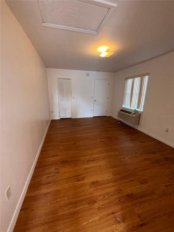An empty room features wood-look flooring, a ceiling light, a window unit, and two doors — 862 CARIBBEAN DRIVE UNIT B, DAVENPORT, FL
