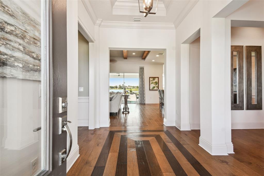 A bright entryway features hardwood floors with a geometric inlay leading toward a rear patio — 5333 LAKE VENICE DRIVE, WIMAUMA, FL