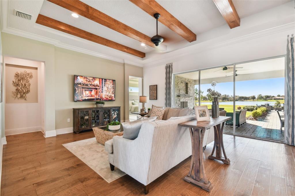 A living room features wood ceiling beams, a television, and sliding glass doors to a patio — 5333 LAKE VENICE DRIVE, WIMAUMA, FL