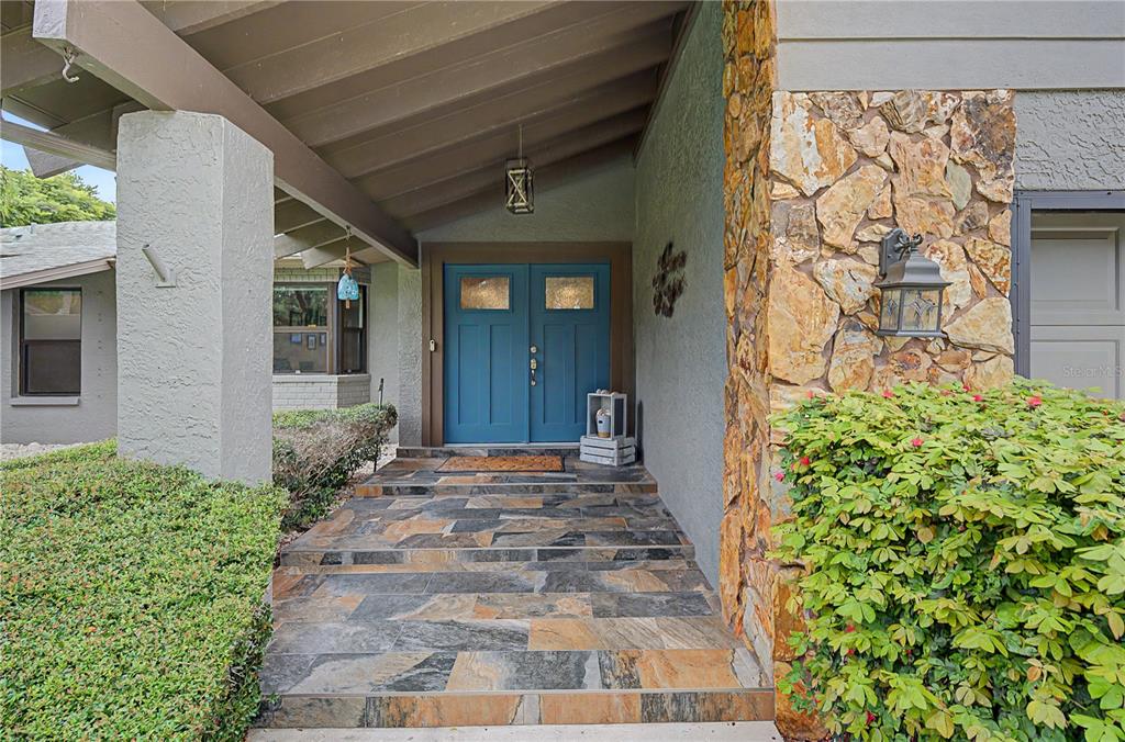 A front entryway features a blue double door, stone flooring, and a stone-clad exterior wall — 1706 AVOCA DRIVE, TARPON SPRINGS, FL