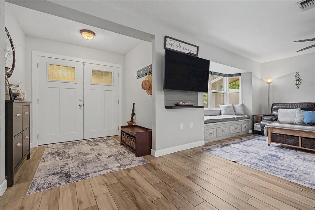 A living room features wood-look tile floors, a double front door, and a built-in window seat — 1706 AVOCA DRIVE, TARPON SPRINGS, FL