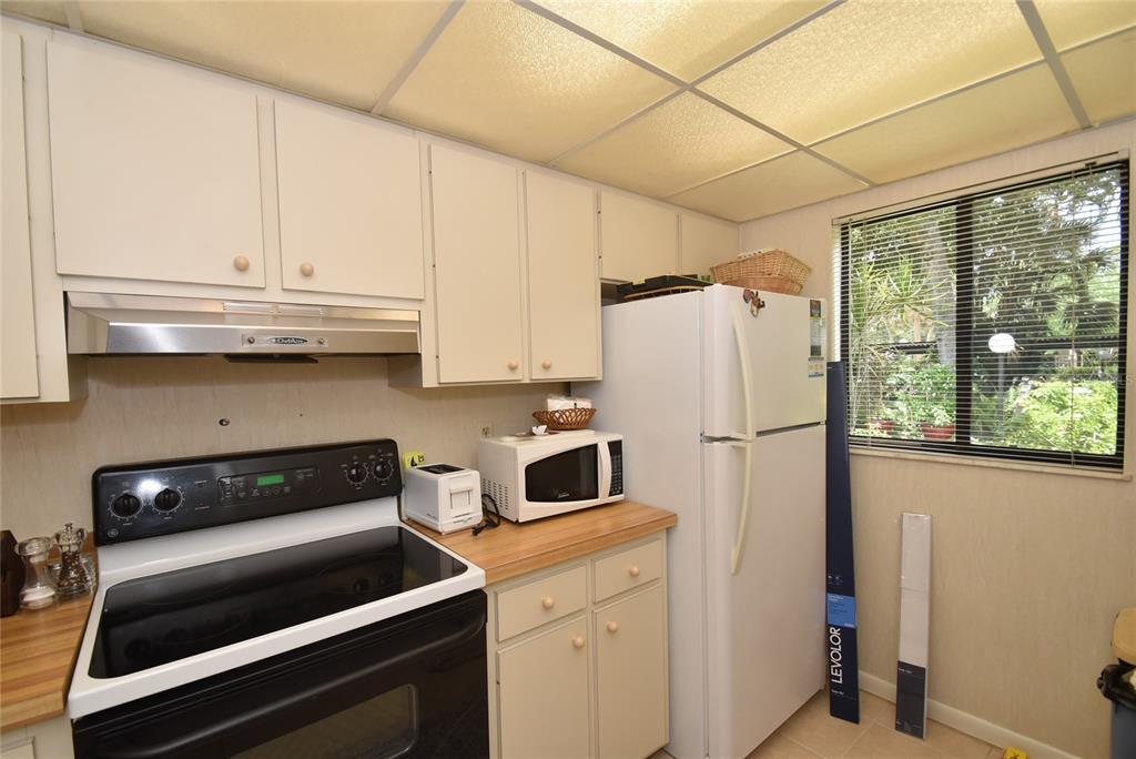 A kitchen features white cabinets, a black electric range, a white refrigerator, and a window — 1709 PELICAN COVE ROAD UNIT GL349, SARASOTA, FL