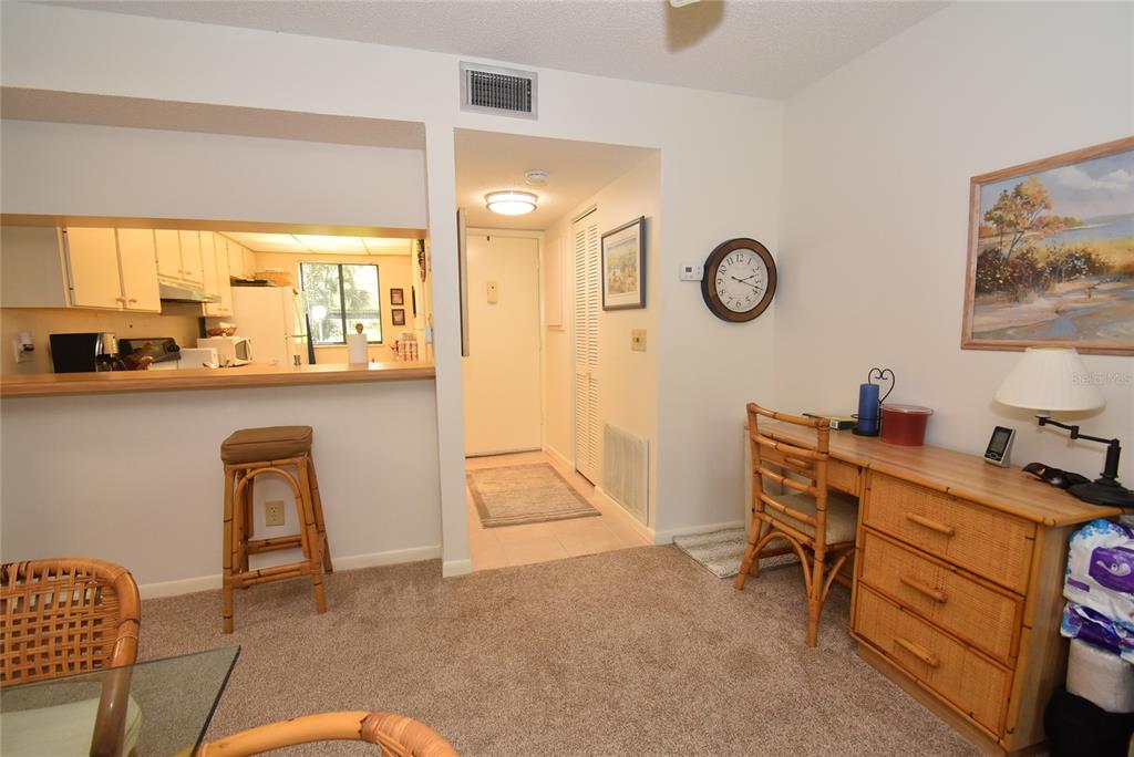 A room with a kitchen pass-through, a desk, a wall clock, and a hallway entrance — 1709 PELICAN COVE ROAD UNIT GL349, SARASOTA, FL
