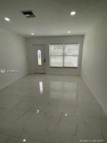 A bright, empty room features white marble-look tile flooring, recessed lighting, and a front entry door — 751 NW 18 Street, Pompano Beach FL 33060, POMPANO BEACH, FL