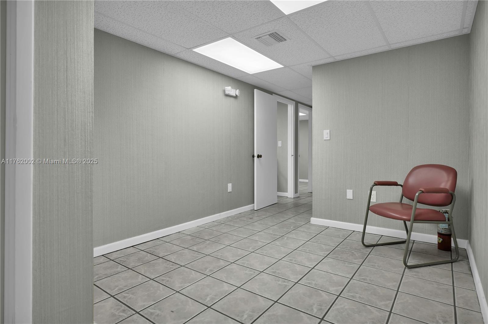 A waiting area features gray textured walls, a tiled floor, and a single red chair — 5220 NW 72nd Ave # A1, Miami FL 33166, MIAMI, FL