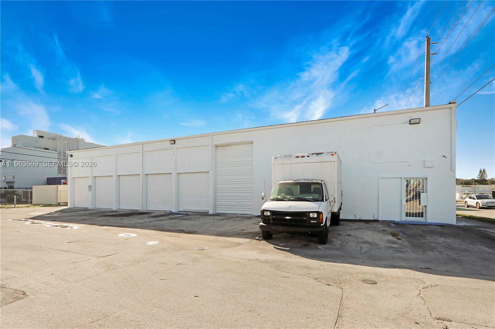 A white industrial warehouse building features multiple roll-up doors and a parked box truck — 9795 NW 7th Ave, Miami FL 33150, MIAMI, FL