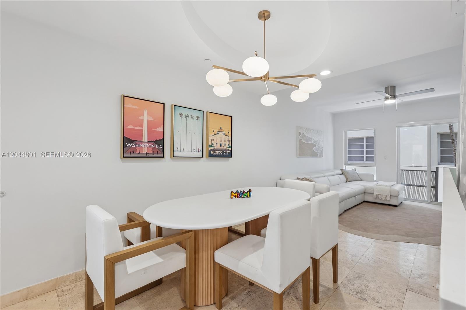 A dining area with a white oval table, modern chandelier, and three framed city posters — 204 Washington Ave # 13, Miami Beach FL 33139, MIAMI BEACH, FL