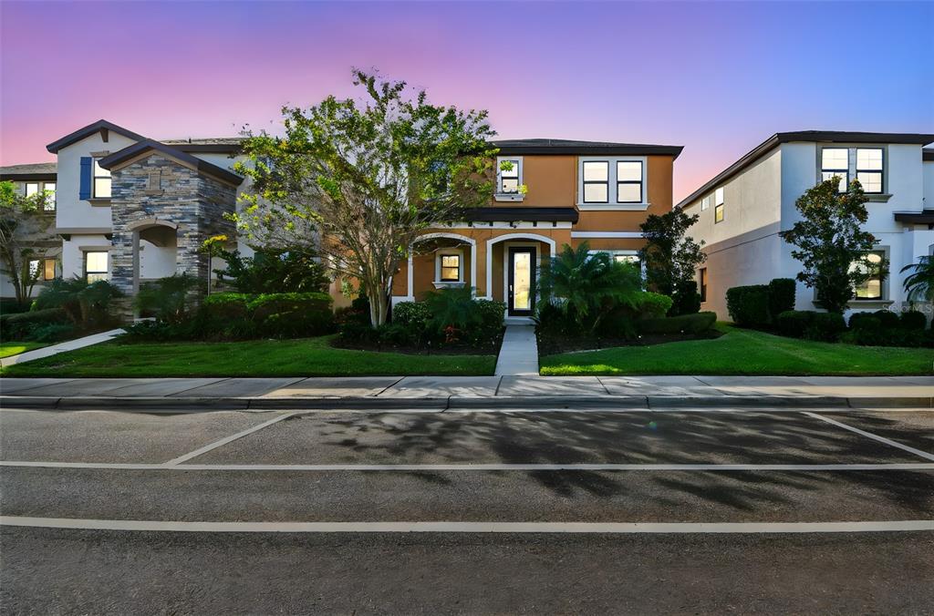 A two-story house with an orange facade and a stone-accented entryway at dusk — 12413 TRIPLE CREEK BOULEVARD, RIVERVIEW, FL