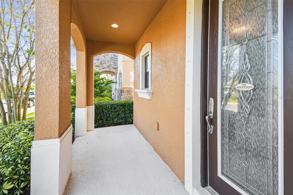 A covered front porch with a brown door featuring decorative glass and a no soliciting sign — 12413 TRIPLE CREEK BOULEVARD, RIVERVIEW, FL