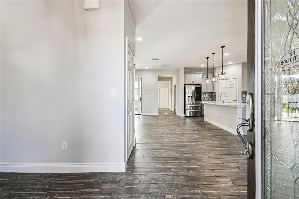 A view from an entryway looking into an open-concept kitchen with wood-look tile flooring — 12413 TRIPLE CREEK BOULEVARD, RIVERVIEW, FL